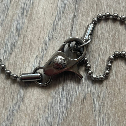 Dolce &amp; Gabbana Cowboy Dog Tag Necklace, model DJ0633. Features a silver-tone metal ball chain and a dog tag with black cowboy-style D&amp;G logo and small “Dolce &amp; Gabbana” text underneath. The front of the tag is patterned with subtle white dots for added detail.