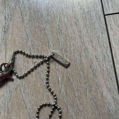 Dolce &amp; Gabbana Cowboy Dog Tag Necklace, model DJ0633. Features a silver-tone metal ball chain and a dog tag with black cowboy-style D&amp;G logo and small “Dolce &amp; Gabbana” text underneath. The front of the tag is patterned with subtle white dots for added detail.