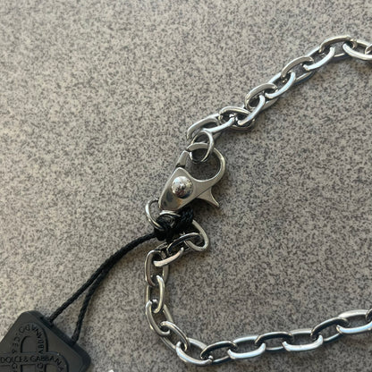 Dolce &amp; Gabbana 2000s Credit Card Necklace (DJ0772) is a rare stainless steel necklace featuring a credit card-shaped pendant. The pendant includes a large raised D&amp;G logo, an engraved D&amp;G logo, and embossed numbers inspired by a real credit card. Finished with a polished metal surface, the necklace comes complete with its original tags and box.