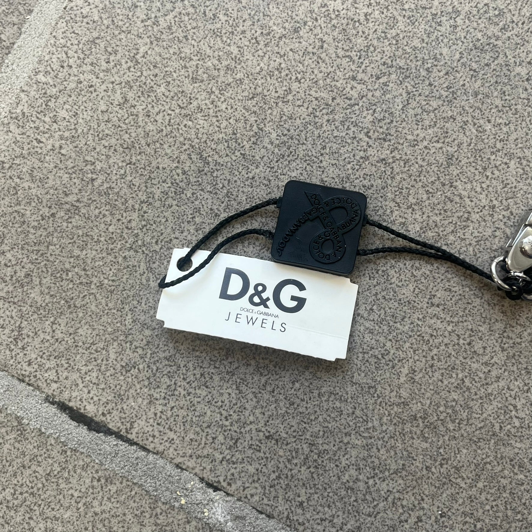 Dolce &amp; Gabbana 2000s Credit Card Necklace (DJ0772) is a rare stainless steel necklace featuring a credit card-shaped pendant. The pendant includes a large raised D&amp;G logo, an engraved D&amp;G logo, and embossed numbers inspired by a real credit card. Finished with a polished metal surface, the necklace comes complete with its original tags and box.