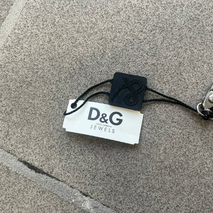 Dolce &amp; Gabbana 2000s Credit Card Necklace (DJ0772) is a rare stainless steel necklace featuring a credit card-shaped pendant. The pendant includes a large raised D&amp;G logo, an engraved D&amp;G logo, and embossed numbers inspired by a real credit card. Finished with a polished metal surface, the necklace comes complete with its original tags and box.