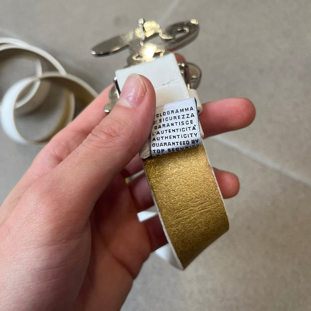 Dolce &amp; Gabbana 2000's Crystal Buckle White Belt features a white leather strap with a stainless steel D&amp;G logo buckle. The buckle has a decorative italic-style font and is fully covered with crystal/rhinestone detailing on the front. Made in Italy.