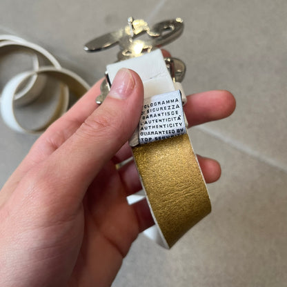 Dolce &amp; Gabbana 2000's Crystal Buckle White Belt features a white leather strap with a stainless steel D&amp;G logo buckle. The buckle has a decorative italic-style font and is fully covered with crystal/rhinestone detailing on the front. Made in Italy.