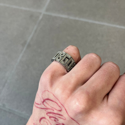 Dolce & Gabbana 2000's Crystal Overlap Ring is a stainless steel ring constructed entirely from cutout D&G letters, forming four repeating D&G sets across 12 letters, each covered in crystals. The ring has slight elasticity, with the letters held together internally by strings.