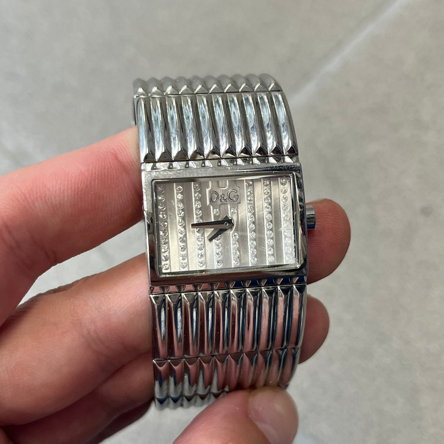 Dolce &amp; Gabbana Crystals Analog Watch is a stainless steel quartz watch featuring a square dial with fully crystal face, silver hands and small D&amp;G logo. The case and bracelet form a continuous design with the face matching the width of the bracelet. The bracelet is made from small silver rectangles. It includes a dual side-clasp closure, is water resistant to 3 ATM, with removable links. Comes with an extra link.