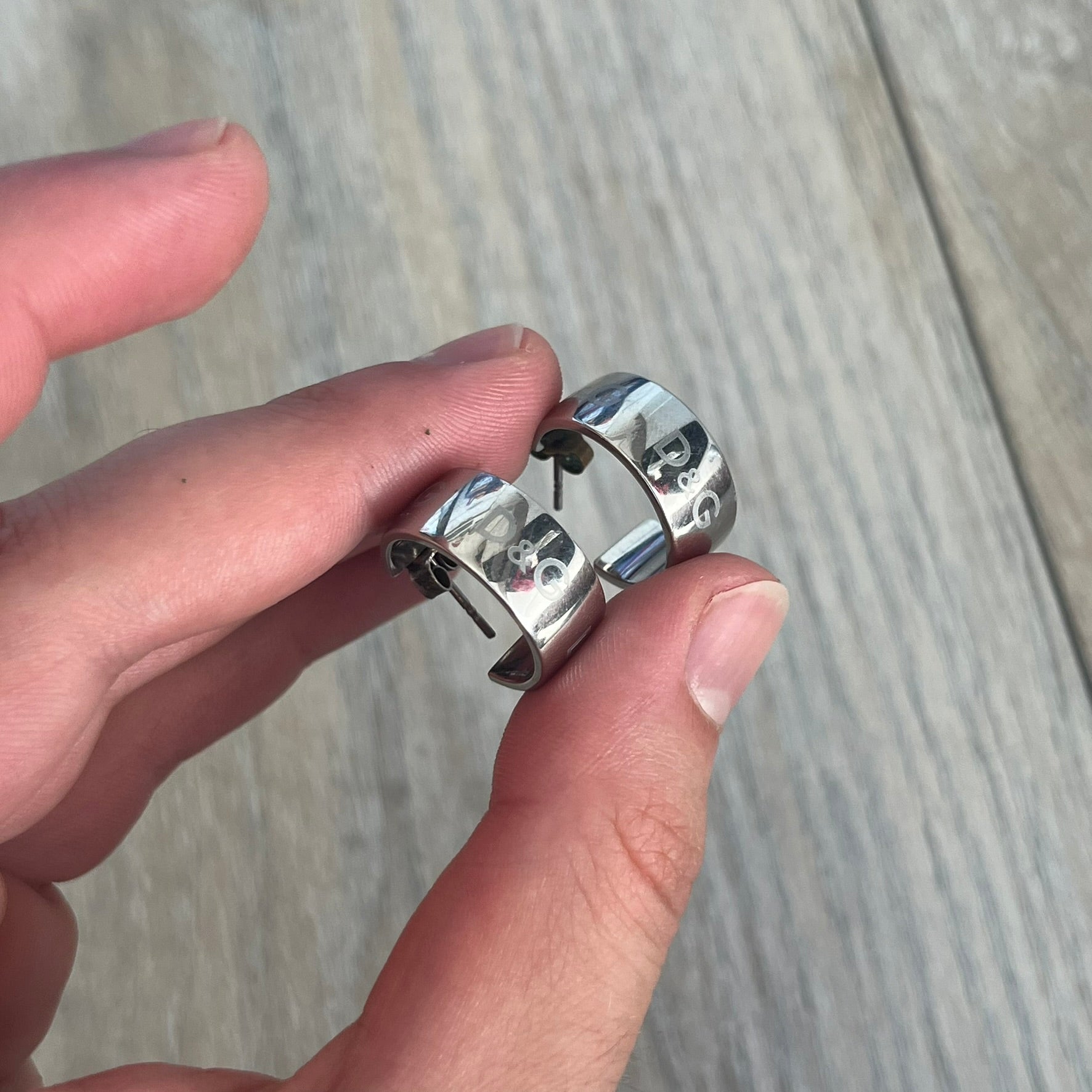Dolce &amp; Gabbana DJ0404 D&amp;G Logo Earrings are a pair of 2000s silver-tone hoop earrings with a wide profile. The earrings feature an engraved repeating D&amp;G logo around the outer surface. They have a hinged hoop design with a straight post closure and a polished metal finish.