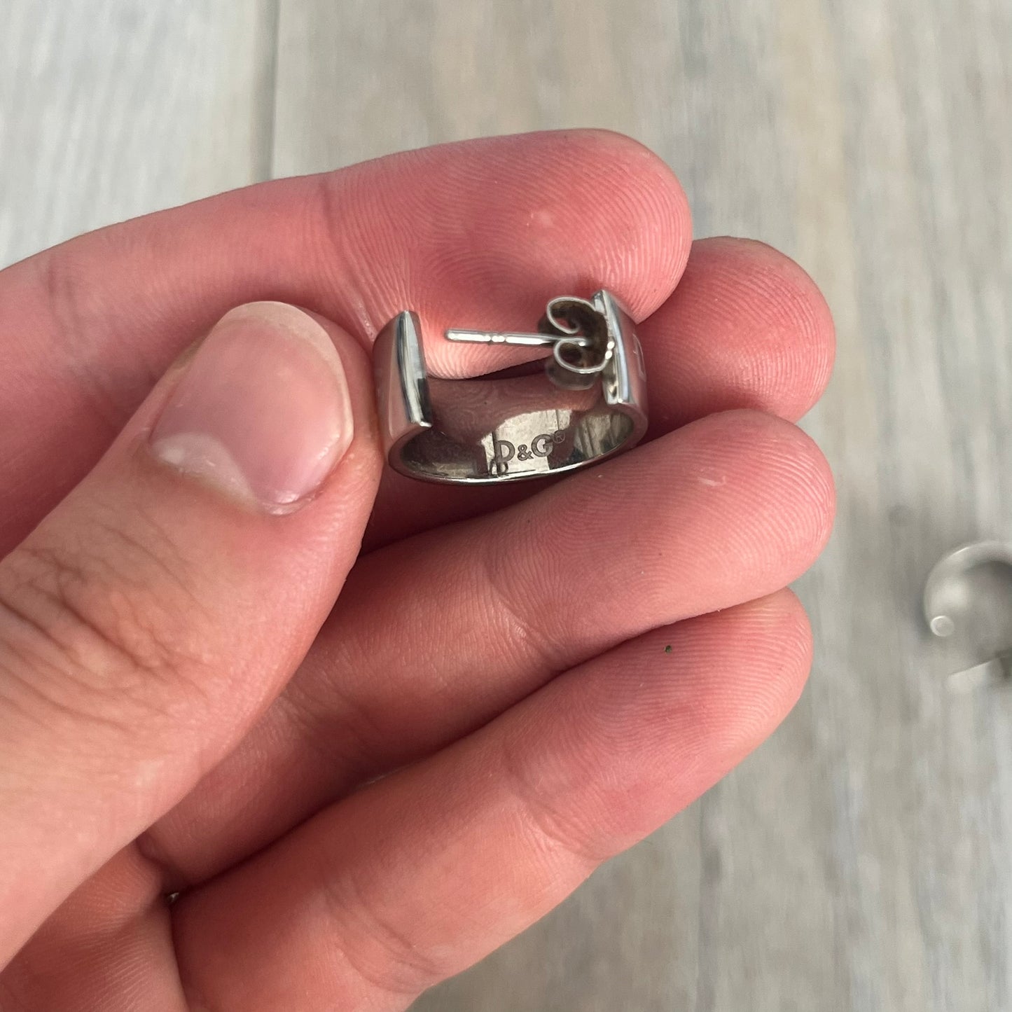 Dolce &amp; Gabbana DJ0404 D&amp;G Logo Earrings are a pair of 2000s silver-tone hoop earrings with a wide profile. The earrings feature an engraved repeating D&amp;G logo around the outer surface. They have a hinged hoop design with a straight post closure and a polished metal finish.