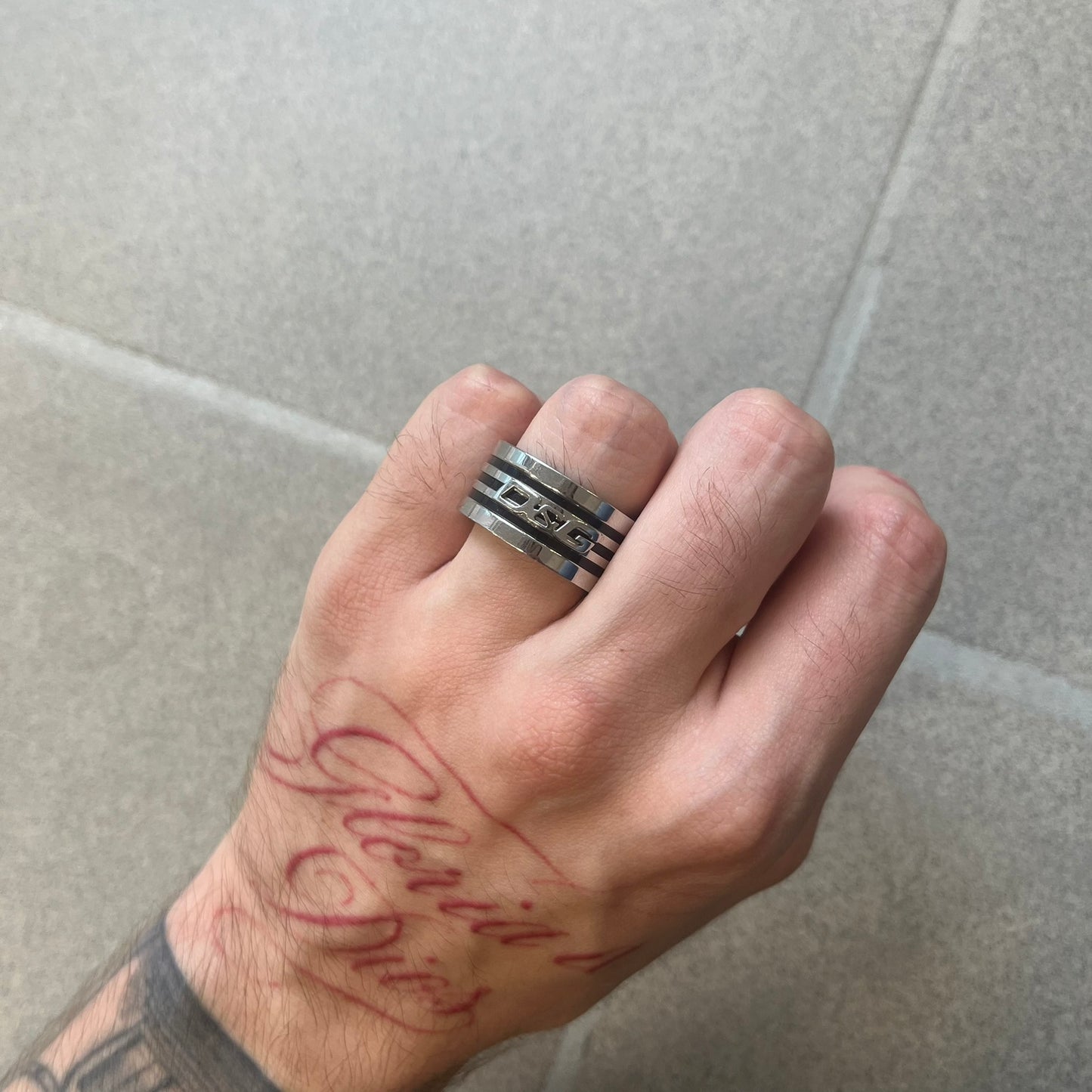Dolce &amp; Gabbana stainless steel ring DJ0709 in silver, featuring three subtle black engraved stripes encircling the band. The D&amp;G logo is displayed in polished silver on top, creating a nice contrast with the dark detailing.