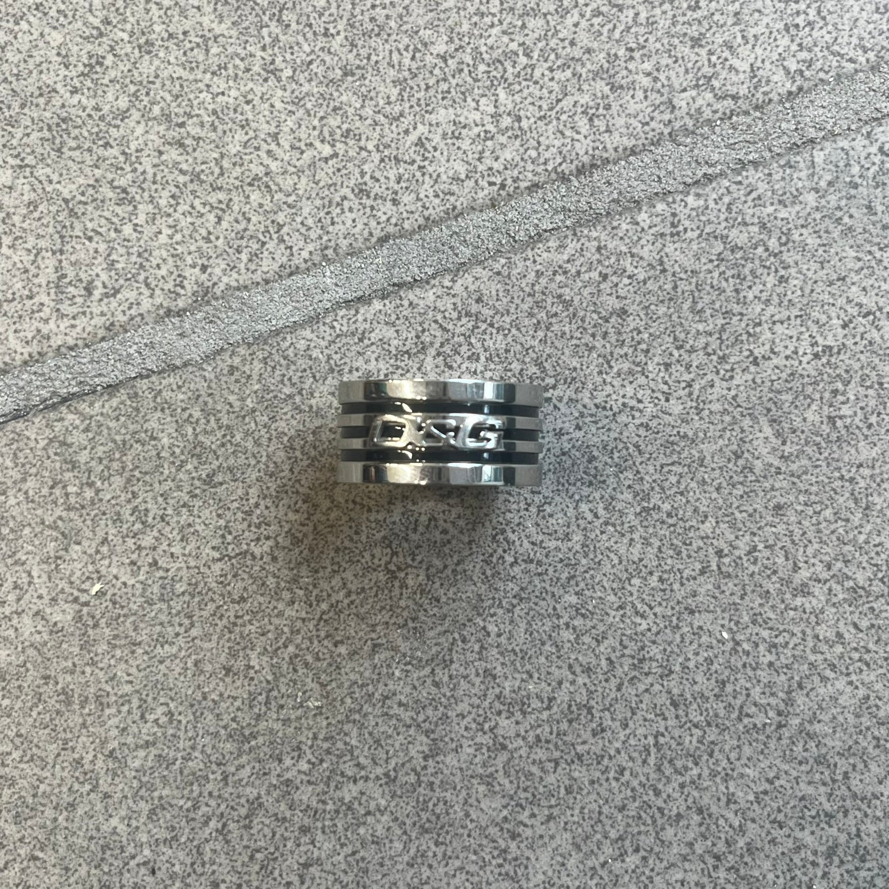 Dolce &amp; Gabbana stainless steel ring DJ0709 in silver, featuring three subtle black engraved stripes encircling the band. The D&amp;G logo is displayed in polished silver on top, creating a nice contrast with the dark detailing.
