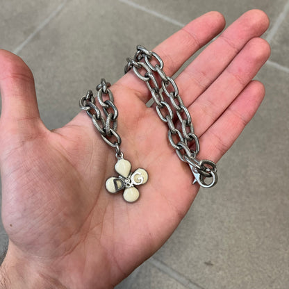 Dolce &amp; Gabbana DJ0879 Four-Leaf Clover Necklace is a stainless steel necklace with a clover pendant that has a stainless steel back and a 3D light beige/cream enamel front. A raised steel D&amp;G logo sits on the front. The oval-link chain alternates between smooth and textured links