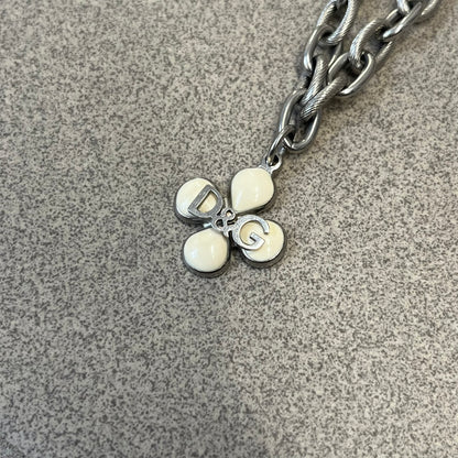 Dolce &amp; Gabbana DJ0879 Four-Leaf Clover Necklace is a stainless steel necklace with a clover pendant that has a stainless steel back and a 3D light beige/cream enamel front. A raised steel D&amp;G logo sits on the front. The oval-link chain alternates between smooth and textured links