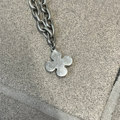 Dolce &amp; Gabbana DJ0879 Four-Leaf Clover Necklace is a stainless steel necklace with a clover pendant that has a stainless steel back and a 3D light beige/cream enamel front. A raised steel D&amp;G logo sits on the front. The oval-link chain alternates between smooth and textured links