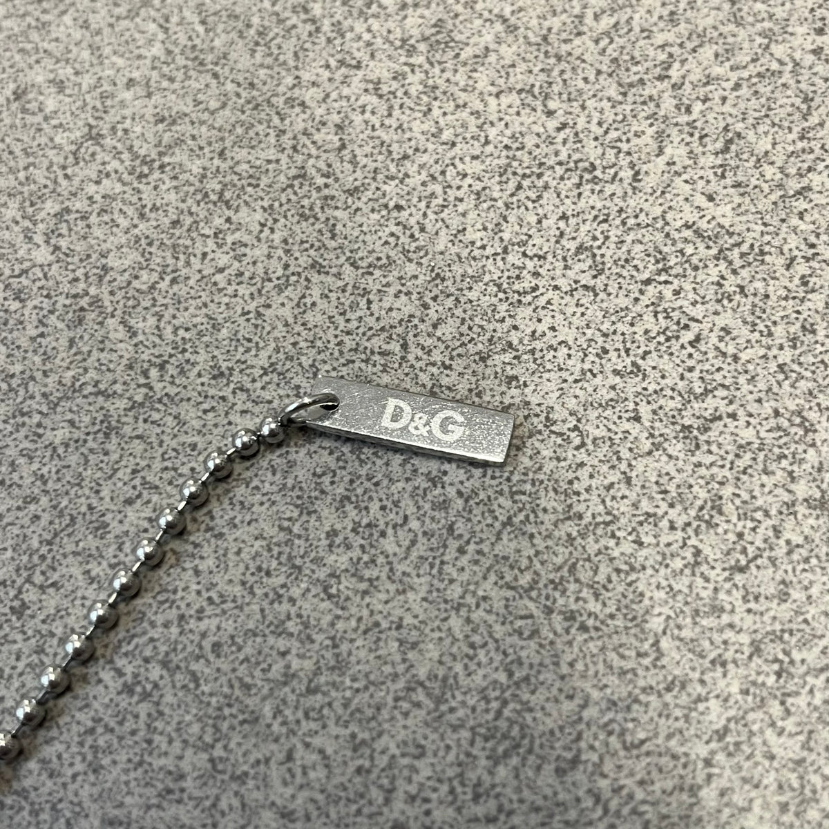 Dolce &amp; Gabbana 2000's Gold Heart DJ0637 Necklace features a stainless steel ball &nbsp;chain, one in silver-tone, the second in gold-tone, with a dog tag-style pendant. The pendant is engraved with a subtle "I" above a gold-tone heart secured by three visible screws, with "D&amp;G" engraved below to form the "I ❤️ D&amp;G" design.&nbsp;