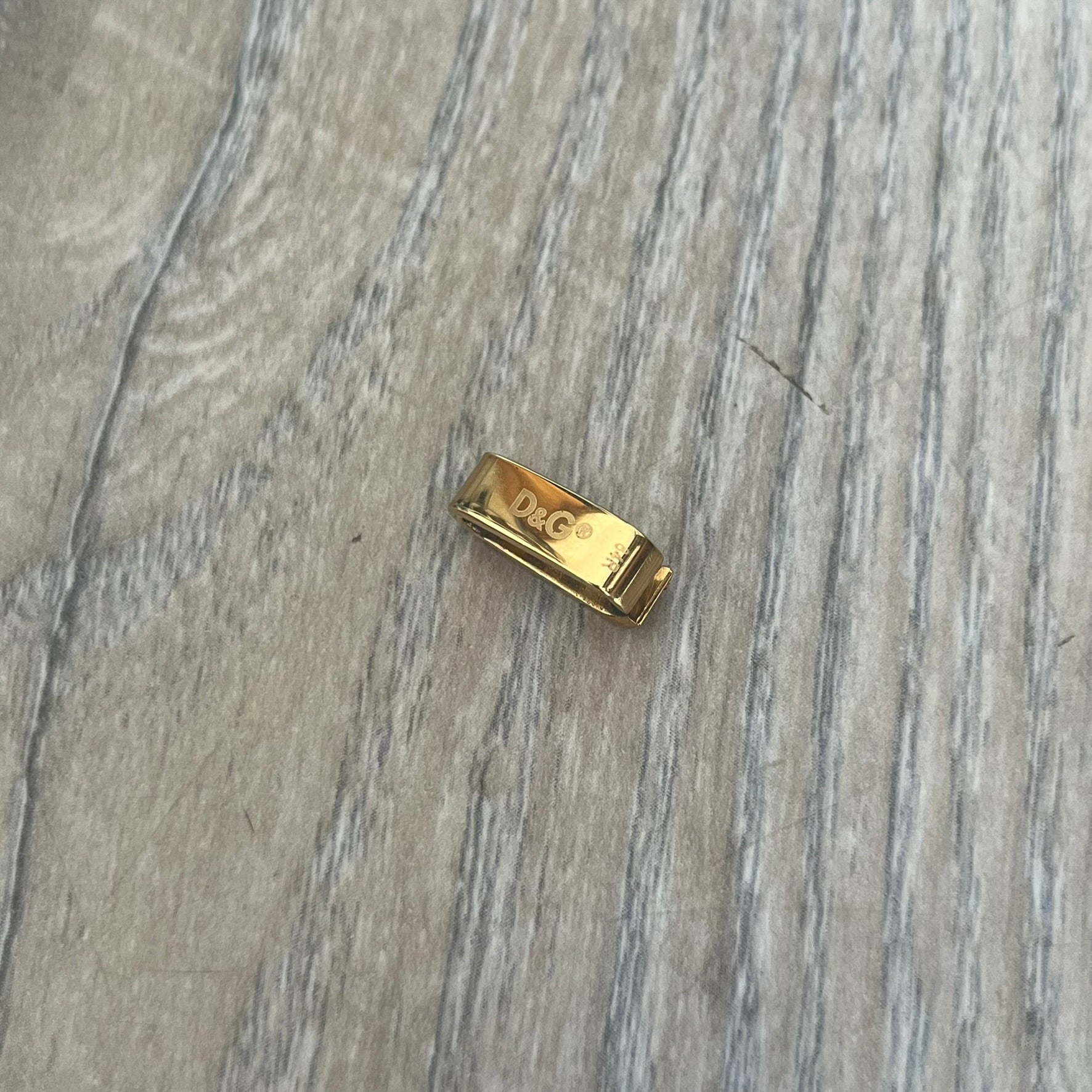 Dolce & Gabbana DJ0680 Gold Rings Set is a 2000s set consisting of four gold-tone rings. Each ring can be worn individually or connected together using the included square D&G clip to form a single four-ring design. The rings have a simple polished finish and come with the original tags.
