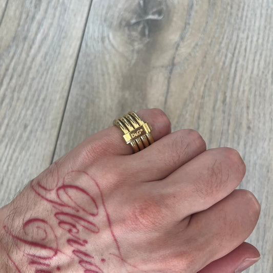 Dolce & Gabbana DJ0680 Gold Rings Set is a 2000s set consisting of four gold-tone rings. Each ring can be worn individually or connected together using the included square D&G clip to form a single four-ring design. The rings have a simple polished finish and come with the original tags.

