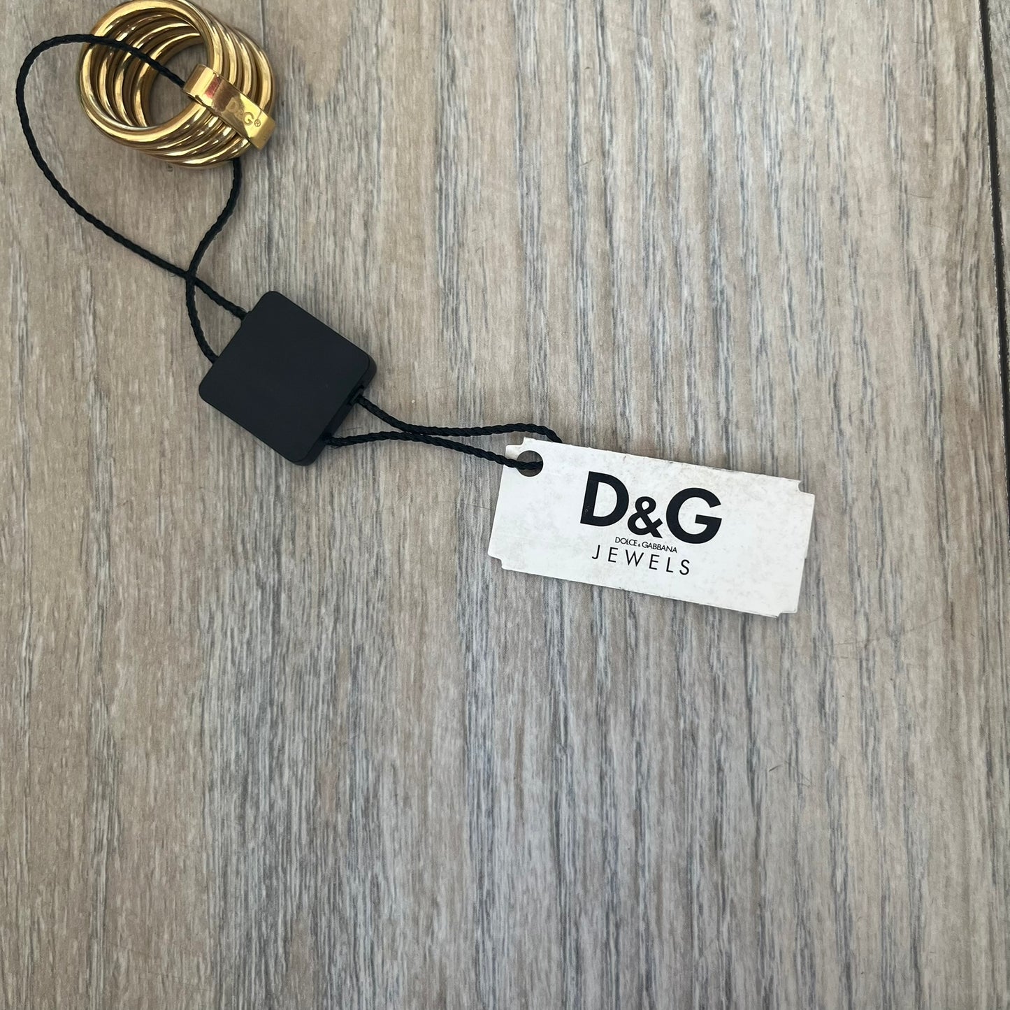 Dolce & Gabbana DJ0680 Gold Rings Set is a 2000s set consisting of four gold-tone rings. Each ring can be worn individually or connected together using the included square D&G clip to form a single four-ring design. The rings have a simple polished finish and come with the original tags.
