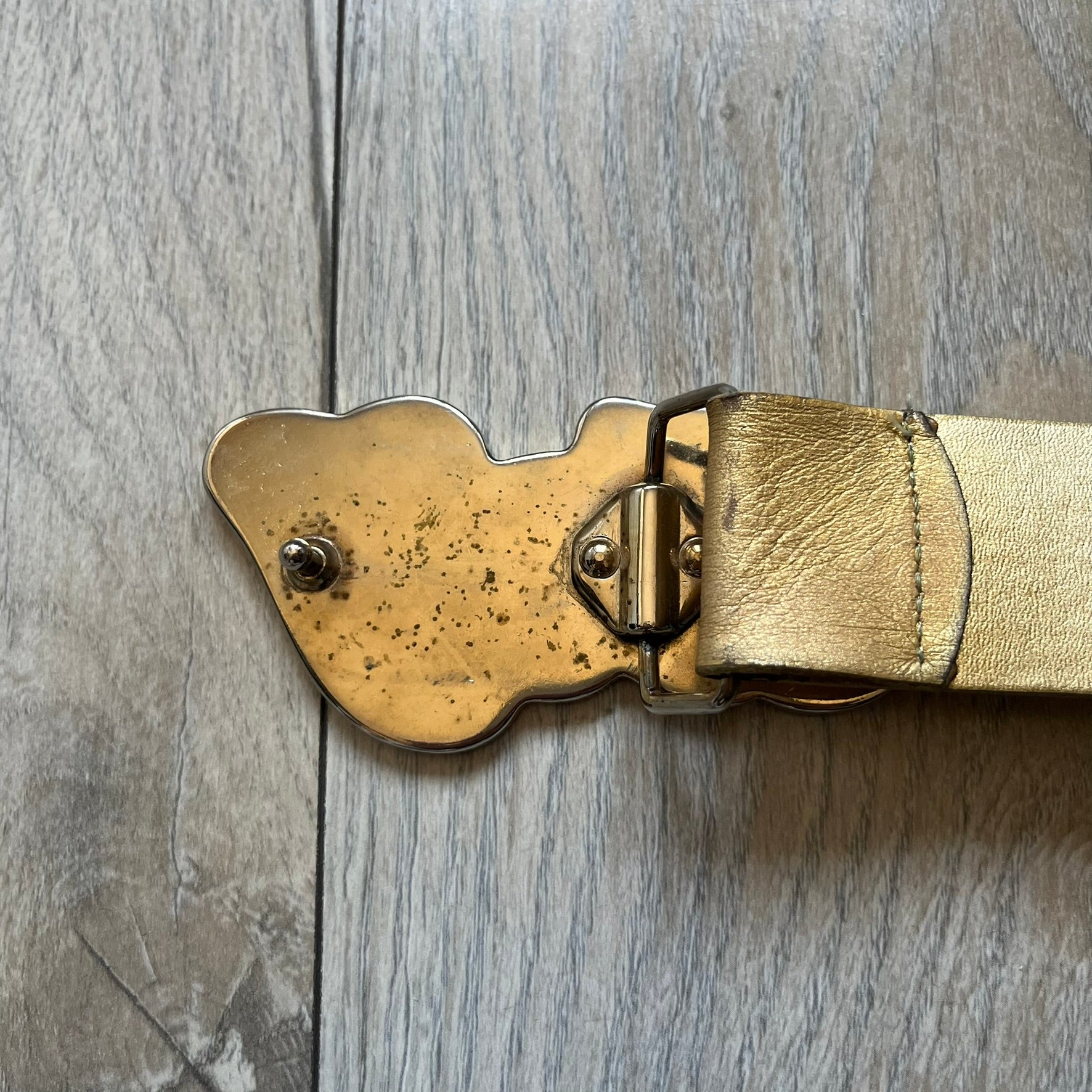 The Dolce &amp; Gabbana 2000’s Gold Tone D&amp;G Logo Belt is made from metallic gold leather and features a large D&amp;G logo buckle shaped directly as the brand’s initials. The buckle uses a cursive D&amp;G logo set over a glittery gold background, framed by a solid gold-tone metal outline. The entire buckle and belt maintain a consistent gold color scheme typical of Dolce &amp; Gabbana accessories from the 2000s.