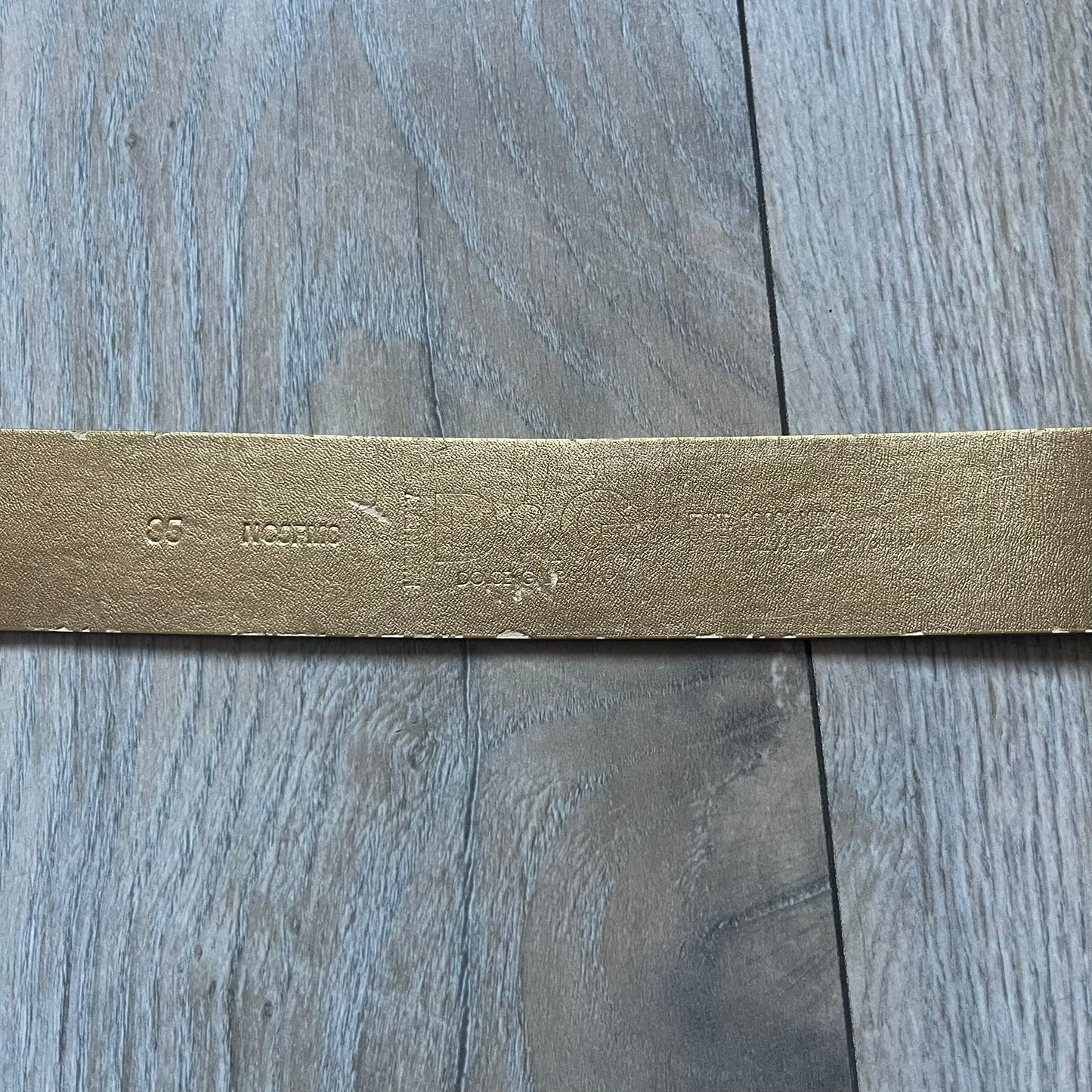 The Dolce & Gabbana 2000’s Gold Tone D&G Logo Belt is made from metallic gold leather and features a large D&G logo buckle shaped directly as the brand’s initials. The buckle uses a cursive D&G logo set over a glittery gold background, framed by a solid gold-tone metal outline. The entire buckle and belt maintain a consistent gold color scheme typical of Dolce & Gabbana accessories from the 2000s.
