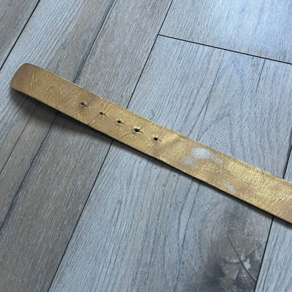 The Dolce & Gabbana 2000’s Gold Tone D&G Logo Belt is made from metallic gold leather and features a large D&G logo buckle shaped directly as the brand’s initials. The buckle uses a cursive D&G logo set over a glittery gold background, framed by a solid gold-tone metal outline. The entire buckle and belt maintain a consistent gold color scheme typical of Dolce & Gabbana accessories from the 2000s.
