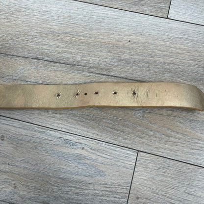 The Dolce &amp; Gabbana 2000’s Gold Tone D&amp;G Logo Belt is made from metallic gold leather and features a large D&amp;G logo buckle shaped directly as the brand’s initials. The buckle uses a cursive D&amp;G logo set over a glittery gold background, framed by a solid gold-tone metal outline. The entire buckle and belt maintain a consistent gold color scheme typical of Dolce &amp; Gabbana accessories from the 2000s.