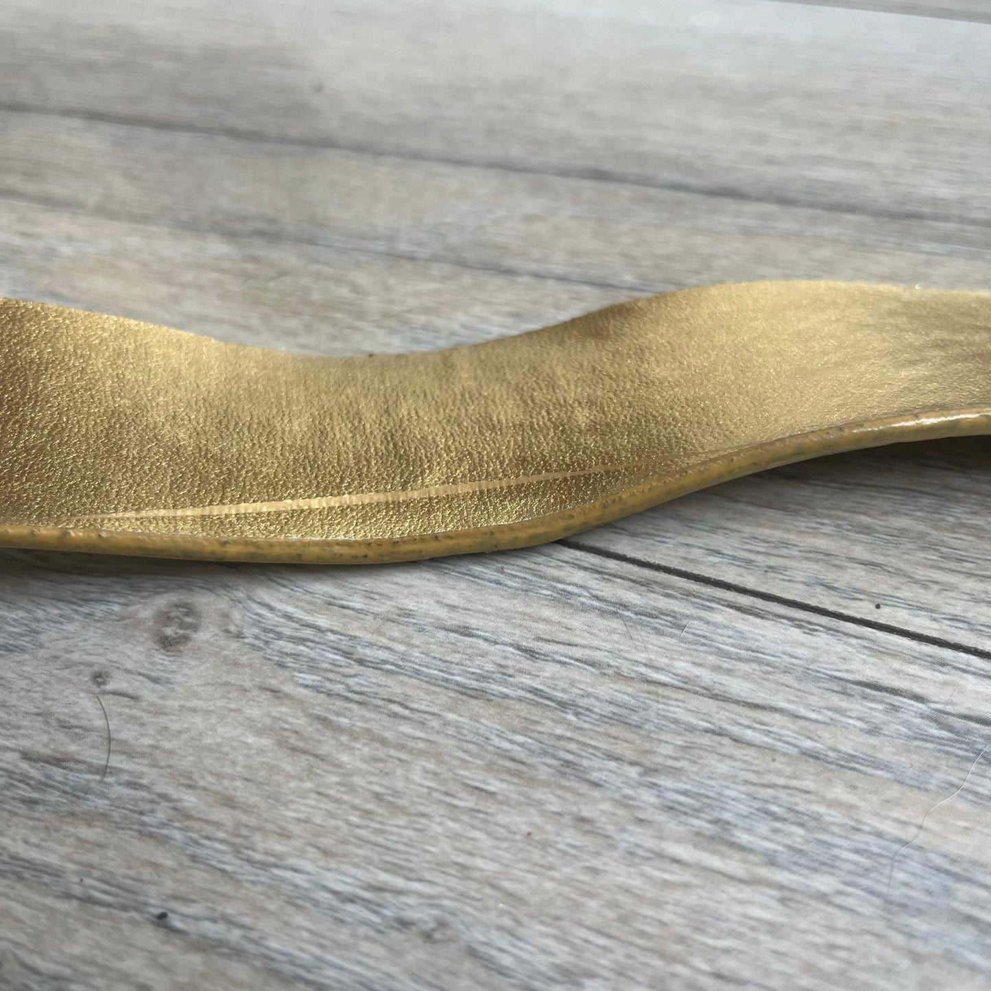 The Dolce &amp; Gabbana 2000’s Gold Tone D&amp;G Logo Belt is made from metallic gold leather and features a large D&amp;G logo buckle shaped directly as the brand’s initials. The buckle uses a cursive D&amp;G logo set over a glittery gold background, framed by a solid gold-tone metal outline. The entire buckle and belt maintain a consistent gold color scheme typical of Dolce &amp; Gabbana accessories from the 2000s.