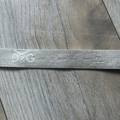 Archive Dolce &amp; Gabbana belt from the 2000s featuring a pretty big metal apple-shaped buckle with a leaf detail, finished in green with silver accents and a small D&amp;G logo. The belt is crafted from white leather with a silver-toned interior, includes a small metal D&amp;G logo at the tip, and is marked Made in Romania. Comes with original tags; the oversized buckle contrasts with the slim belt width.