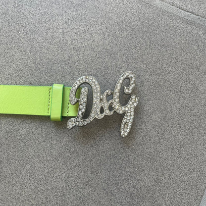 Dolce &amp; Gabbana 2000s Green Crystal Buckle Belt features a lime green leather strap with a stainless steel D&amp;G logo buckle. The buckle has a decorative italic-style font and is fully covered with crystal/rhinestone detailing on the front. Made in Italy.