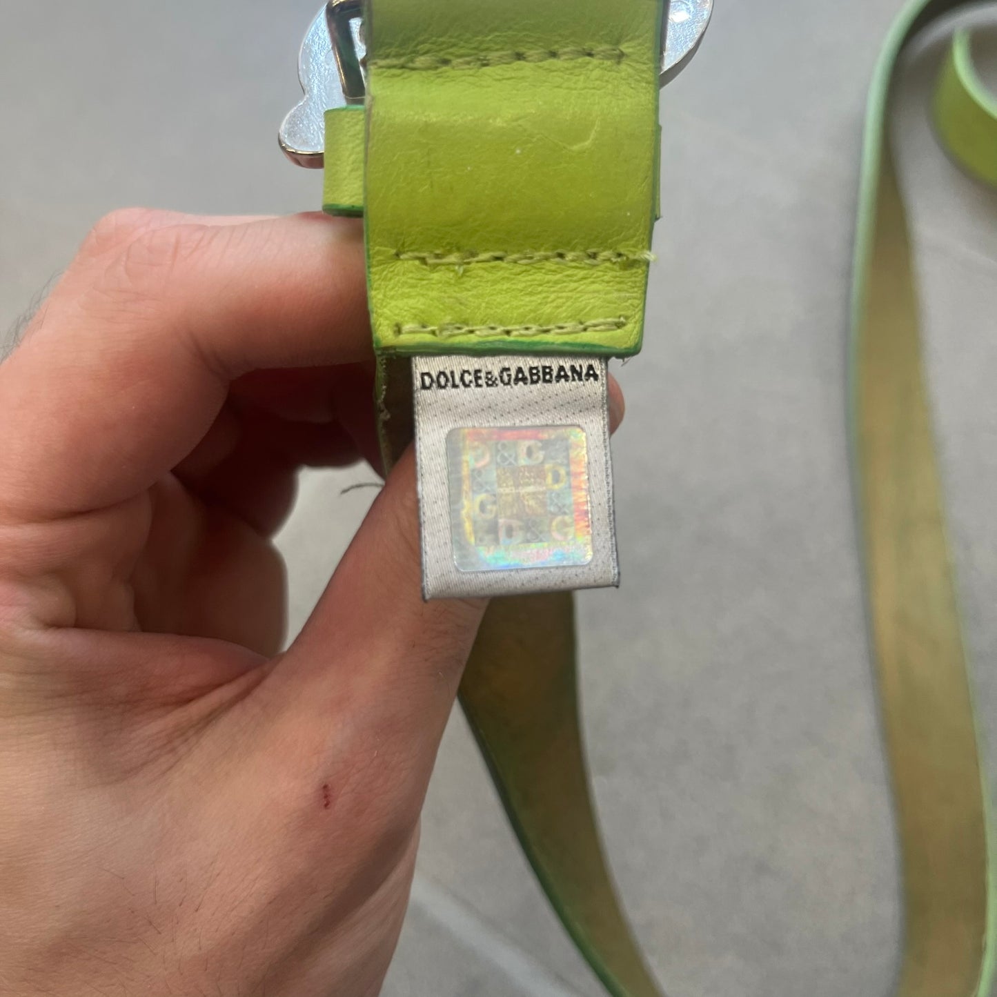 Dolce &amp; Gabbana 2000s Green Crystal Buckle Belt features a lime green leather strap with a stainless steel D&amp;G logo buckle. The buckle has a decorative italic-style font and is fully covered with crystal/rhinestone detailing on the front. Made in Italy.