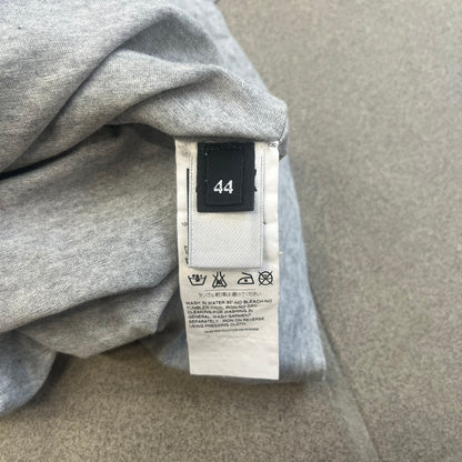 Dolce &amp; Gabbana 2000's Kim Basinger Tee is a gray T-shirt with a photo of Kim Basinger on the front and small “Herb Ritts Foundation” text below it. The lower back has D&amp;G text logo. The shirt is constructed inside-out style, with the stitching visible along the sides.