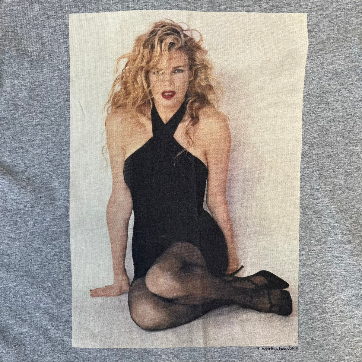 Dolce &amp; Gabbana 2000's Kim Basinger Tee is a gray T-shirt with a photo of Kim Basinger on the front and small “Herb Ritts Foundation” text below it. The lower back has D&amp;G text logo. The shirt is constructed inside-out style, with the stitching visible along the sides.