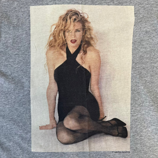 Dolce &amp; Gabbana 2000's Kim Basinger Tee is a gray T-shirt with a photo of Kim Basinger on the front and small “Herb Ritts Foundation” text below it. The lower back has D&amp;G text logo. The shirt is constructed inside-out style, with the stitching visible along the sides.