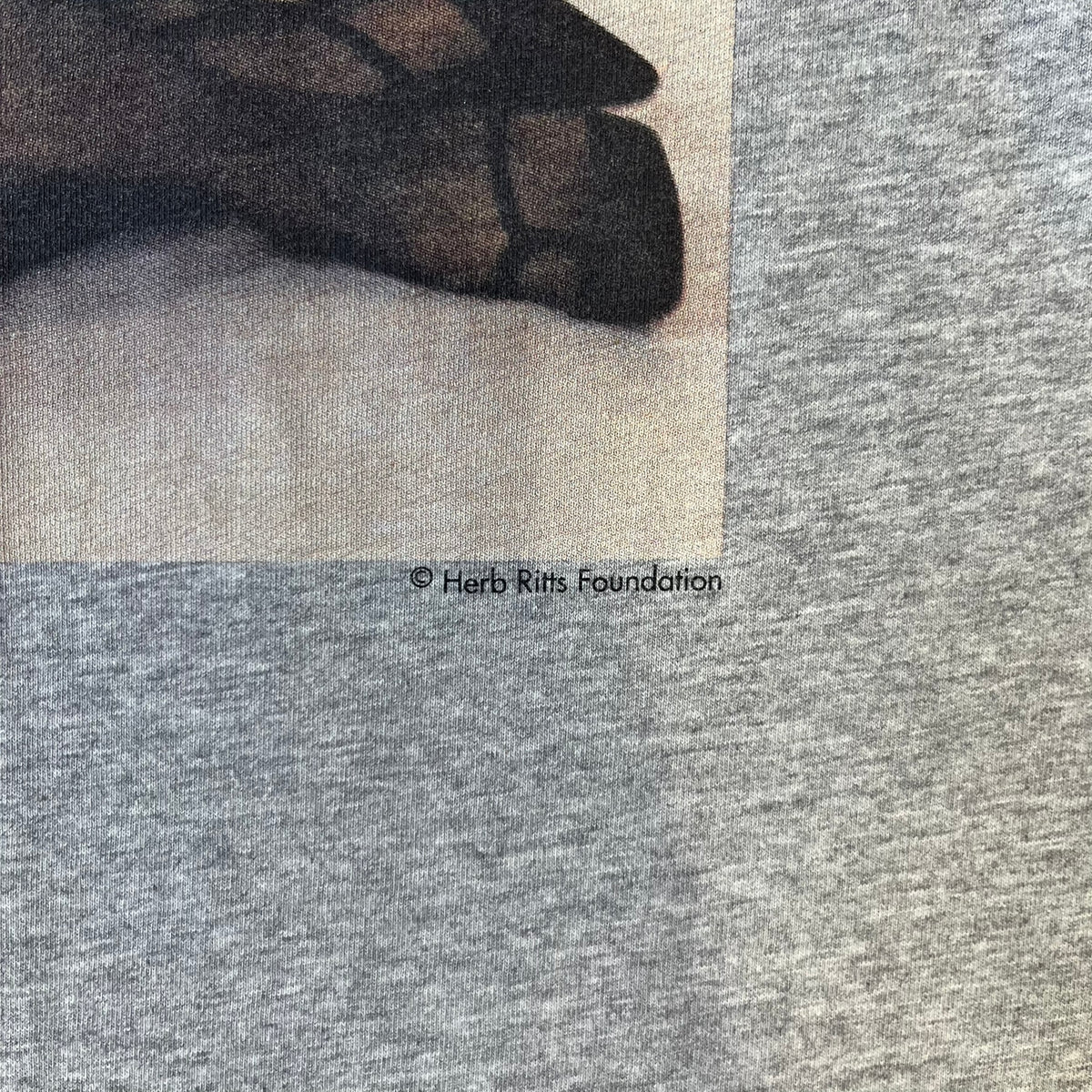 Dolce &amp; Gabbana 2000's Kim Basinger Tee is a gray T-shirt with a photo of Kim Basinger on the front and small “Herb Ritts Foundation” text below it. The lower back has D&amp;G text logo. The shirt is constructed inside-out style, with the stitching visible along the sides.