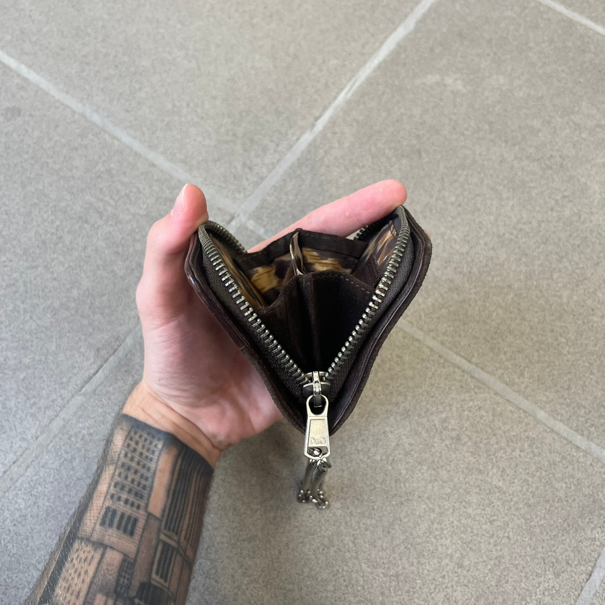 Dolce & Gabbana 2000's Leather Chain Wallet is made in Italy from a combination of suede and shiny leather, featuring two visible screw details and a D&G logo on the leather portion. The interior includes two pockets and a leather tag, with an attached chain.