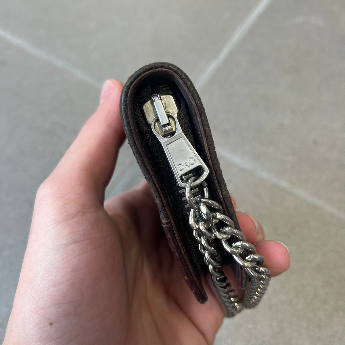 Dolce & Gabbana 2000's Leather Chain Wallet is made in Italy from a combination of suede and shiny leather, featuring two visible screw details and a D&G logo on the leather portion. The interior includes two pockets and a leather tag, with an attached chain.