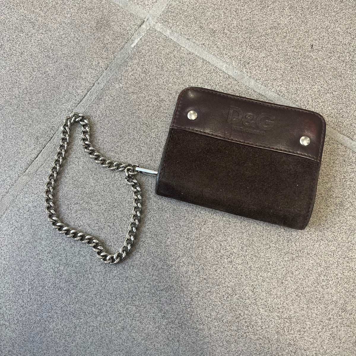 Dolce & Gabbana 2000's Leather Chain Wallet is made in Italy from a combination of suede and shiny leather, featuring two visible screw details and a D&G logo on the leather portion. The interior includes two pockets and a leather tag, with an attached chain.