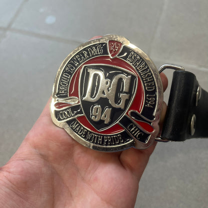 Dolce &amp; Gabbana "Made with Pride" Belt features a circular silver buckle with D&amp;G 94 at the center, surrounded by “Proud to Wear D&amp;G,” “Made with Pride,” and “Established 1994” text. Finished with subtle red and navy accents, it comes with a non-D&amp;G basic black leather belt.