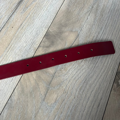 Dolce & Gabbana 2000s Moto Biker Leather Belt is a dark red leather belt made in Italy. The bronze-tone buckle features blue and red enamel detailing, with a biker graphic in the center on a red background. Above the rider is “GOD SAVE THE RIDER” text on a blue background. The buckle is finished with star detailing. Made from 100% leather.