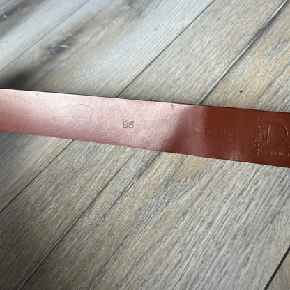 Dolce & Gabbana 2000s Moto Biker Leather Belt is a dark red leather belt made in Italy. The bronze-tone buckle features blue and red enamel detailing, with a biker graphic in the center on a red background. Above the rider is “GOD SAVE THE RIDER” text on a blue background. The buckle is finished with star detailing. Made from 100% leather.