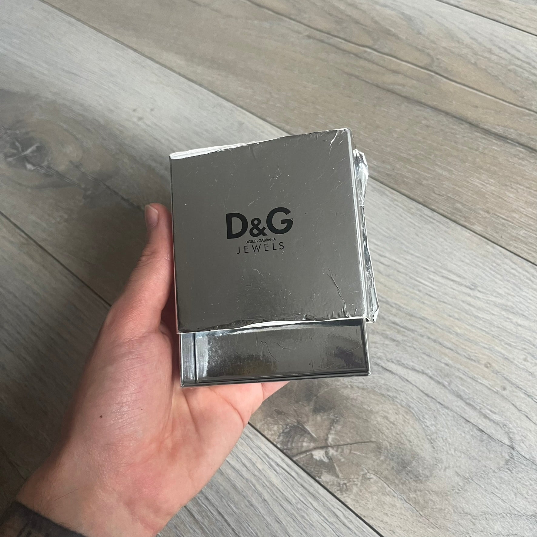 Dolce & Gabbana 2000s Padlock Leather Bracelet is a brown leather bracelet with an adjustable closure and multiple sizing holes. It features two metal loops, with a D&G engraved padlock attached to one loop and two metal keys attached to the other. The bracelet comes with its original box.
