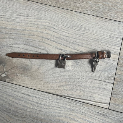 Dolce & Gabbana 2000s Padlock Leather Bracelet is a brown leather bracelet with an adjustable closure and multiple sizing holes. It features two metal loops, with a D&G engraved padlock attached to one loop and two metal keys attached to the other. The bracelet comes with its original box.
