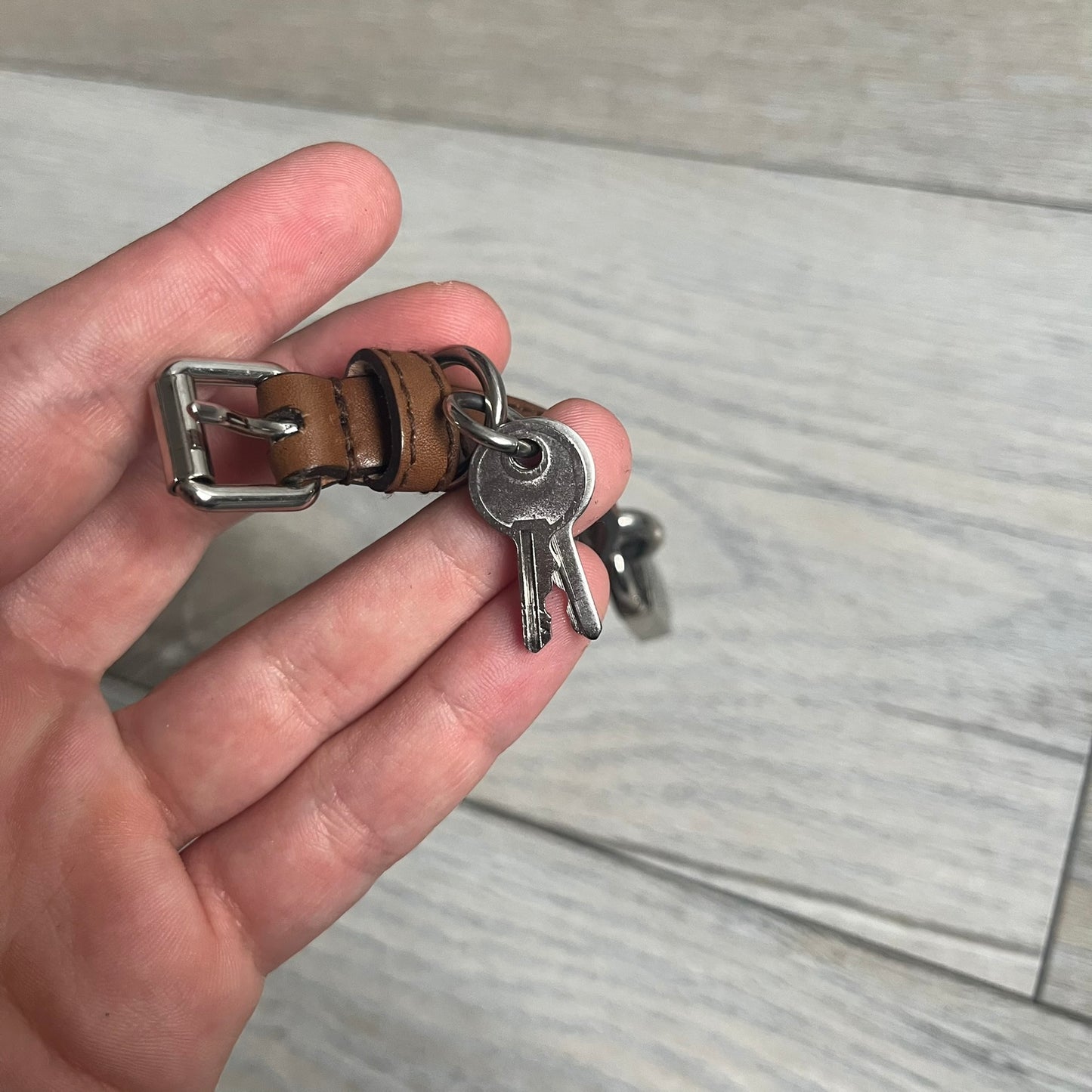 Dolce & Gabbana 2000s Padlock Leather Bracelet is a brown leather bracelet with an adjustable closure and multiple sizing holes. It features two metal loops, with a D&G engraved padlock attached to one loop and two metal keys attached to the other. The bracelet comes with its original box.
