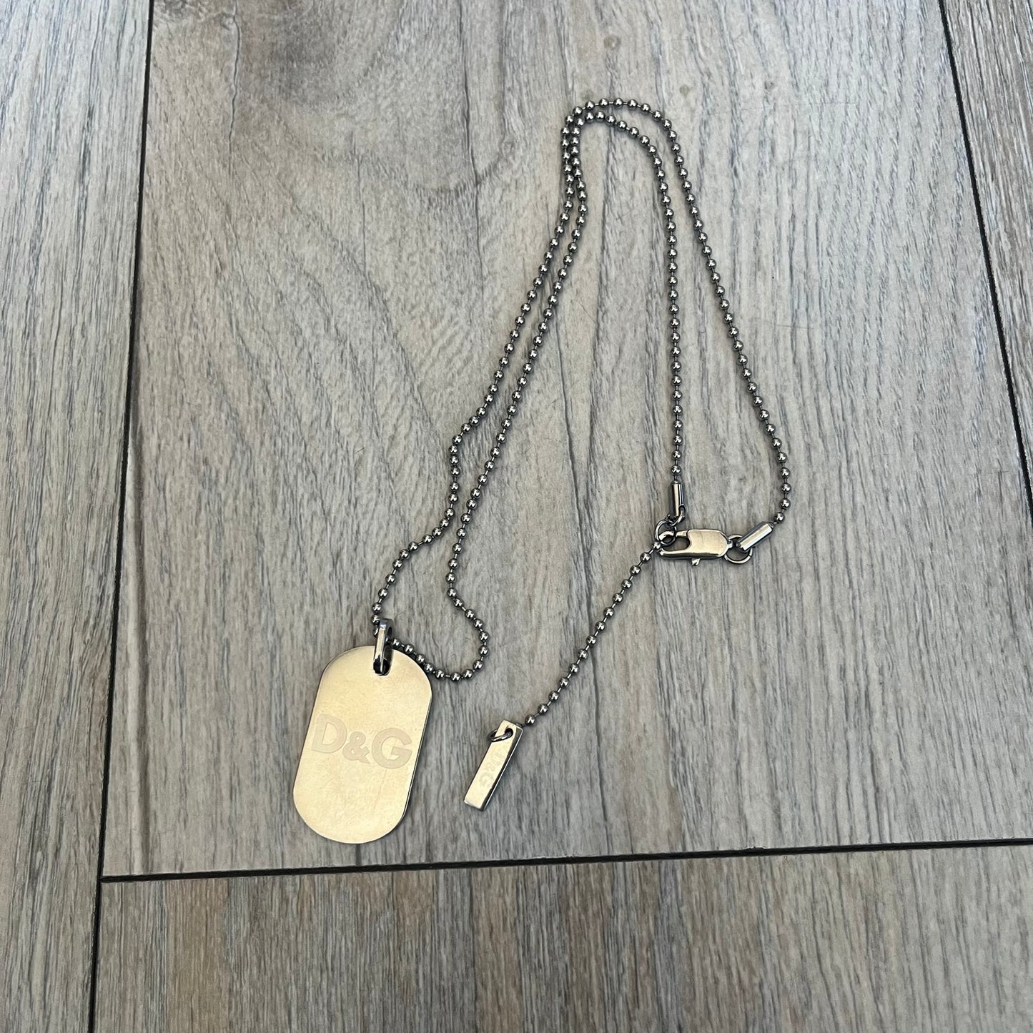 Dolce &amp; Gabbana plain logo dog tag necklace in silver-tone stainless steel, featuring the iconic D&amp;G logo engraved on a sleek tag. Suspended on a classic ball chain with a regulated size. A versatile accessory that combines minimal branding with everyday wearability.