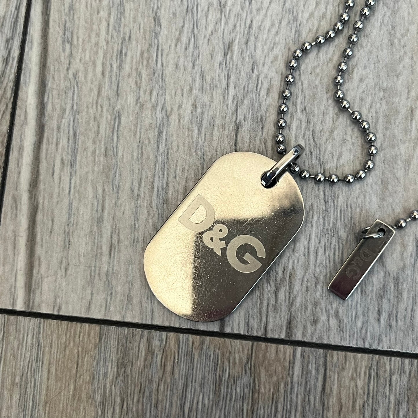 Dolce &amp; Gabbana plain logo dog tag necklace in silver-tone stainless steel, featuring the iconic D&amp;G logo engraved on a sleek tag. Suspended on a classic ball chain with a regulated size. A versatile accessory that combines minimal branding with everyday wearability.
