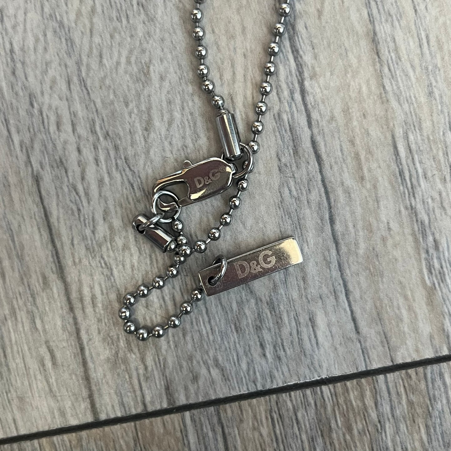 Dolce &amp; Gabbana plain logo dog tag necklace in silver-tone stainless steel, featuring the iconic D&amp;G logo engraved on a sleek tag. Suspended on a classic ball chain with a regulated size. A versatile accessory that combines minimal branding with everyday wearability.