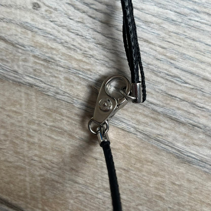 Dolce & Gabbana 2000s Radiator Necklace DJ0705 is a necklace featuring a square-link chain combined with a black leather cord. The pendant is made from stainless steel with a square frame design that includes black and silver line detailing resembling a radiator structure. A raised D&G logo is positioned in the center of the ID plate, while the back is black, visible through the open metal line design.