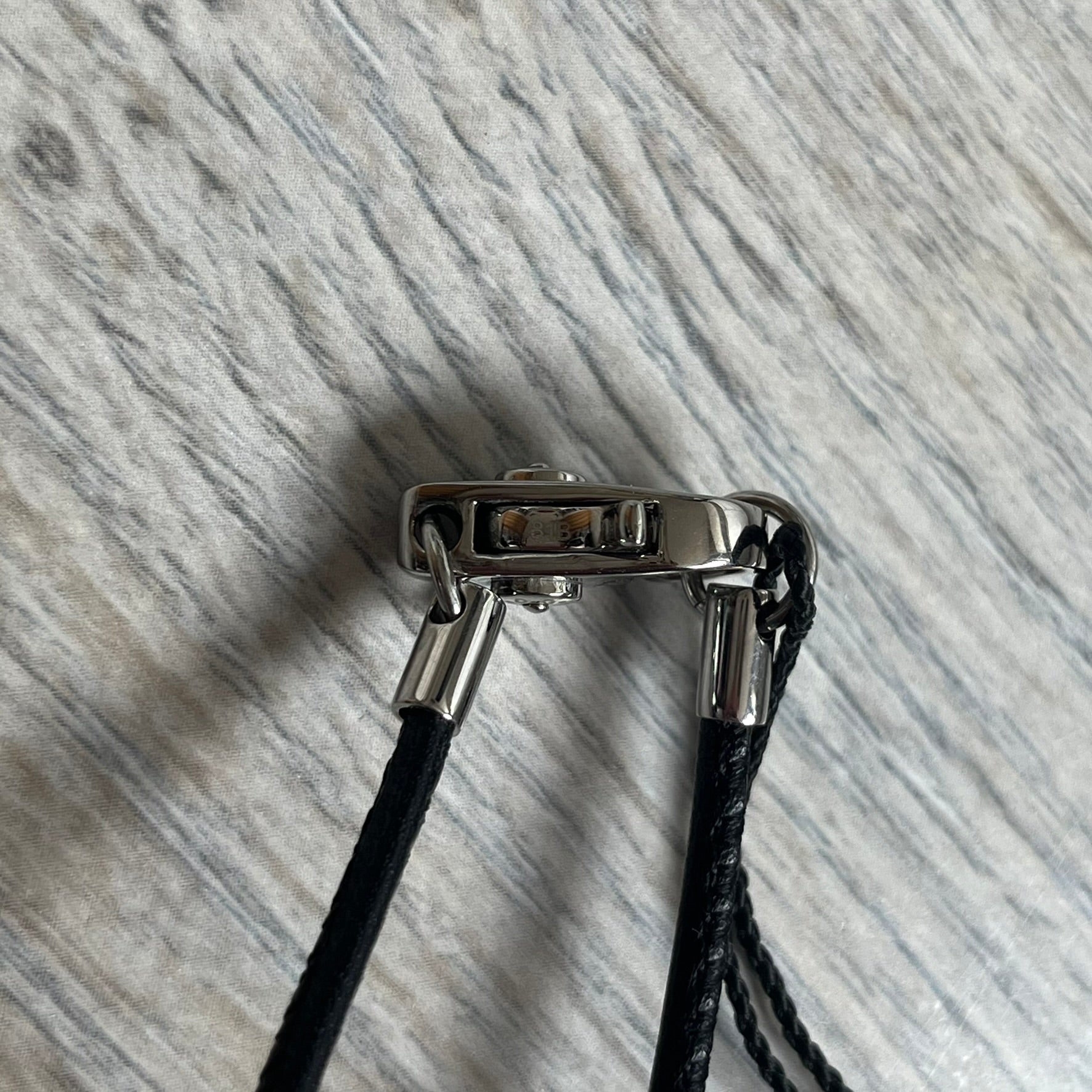 Dolce & Gabbana 2000s Radiator Necklace DJ0705 is a necklace featuring a square-link chain combined with a black leather cord. The pendant is made from stainless steel with a square frame design that includes black and silver line detailing resembling a radiator structure. A raised D&G logo is positioned in the center of the ID plate, while the back is black, visible through the open metal line design.