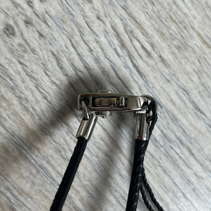 Dolce & Gabbana 2000s Radiator Necklace DJ0705 is a necklace featuring a square-link chain combined with a black leather cord. The pendant is made from stainless steel with a square frame design that includes black and silver line detailing resembling a radiator structure. A raised D&G logo is positioned in the center of the ID plate, while the back is black, visible through the open metal line design.
