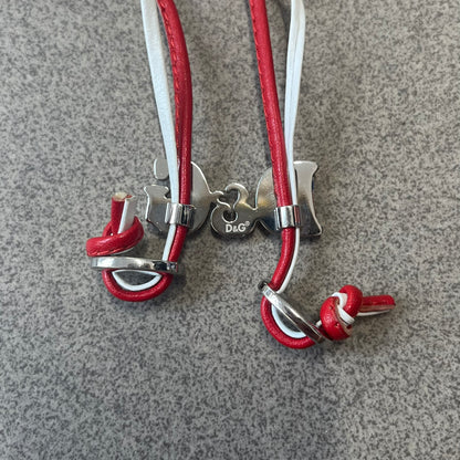 Dolce &amp; Gabbana 2000s Red &amp; White Strings Necklace &amp; Bracelet is a versatile accessory featuring red and white leather cords joined with stainless steel end caps. The center is finished with a stainless steel D&amp;G logo, while the back of the logo features a small engraved D&amp;G mark. Designed to be worn either as a necklace or wrapped as a bracelet.