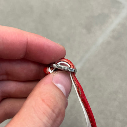 Dolce &amp; Gabbana 2000s Red &amp; White Strings Necklace &amp; Bracelet is a versatile accessory featuring red and white leather cords joined with stainless steel end caps. The center is finished with a stainless steel D&amp;G logo, while the back of the logo features a small engraved D&amp;G mark. Designed to be worn either as a necklace or wrapped as a bracelet, it comes complete with its original box.