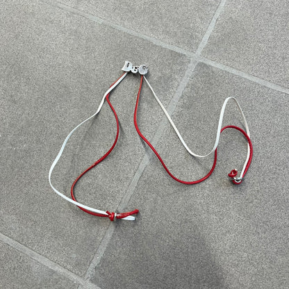 Dolce &amp; Gabbana 2000s Red &amp; White Strings Necklace &amp; Bracelet is a versatile accessory featuring red and white leather cords joined with stainless steel end caps. The center is finished with a stainless steel D&amp;G logo, while the back of the logo features a small engraved D&amp;G mark. Designed to be worn either as a necklace or wrapped as a bracelet, it comes complete with its original box.